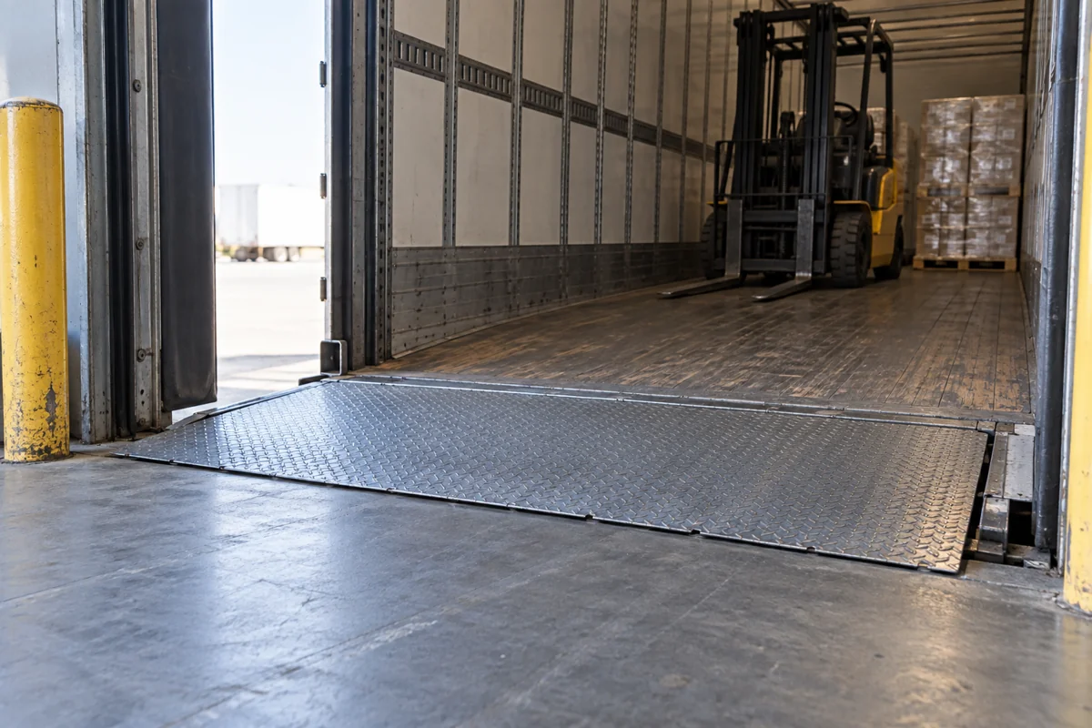 A loading dock floor transition beside stationary warehouse equipment